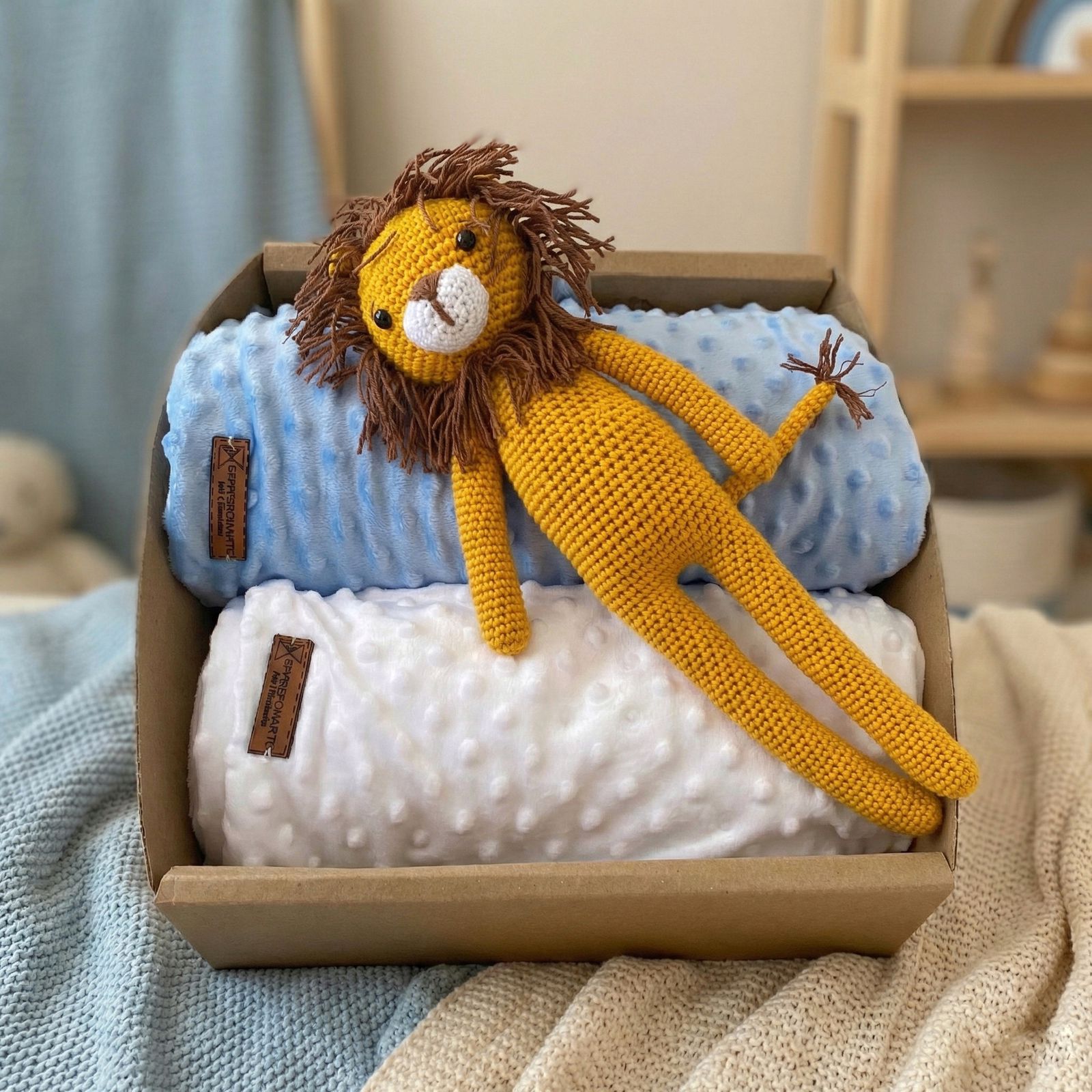 Caja regalo para bebé con dos mantas minky con textura de puntos (azul y blanco) y león tejido a mano amigurumi amarillo con melena café encima