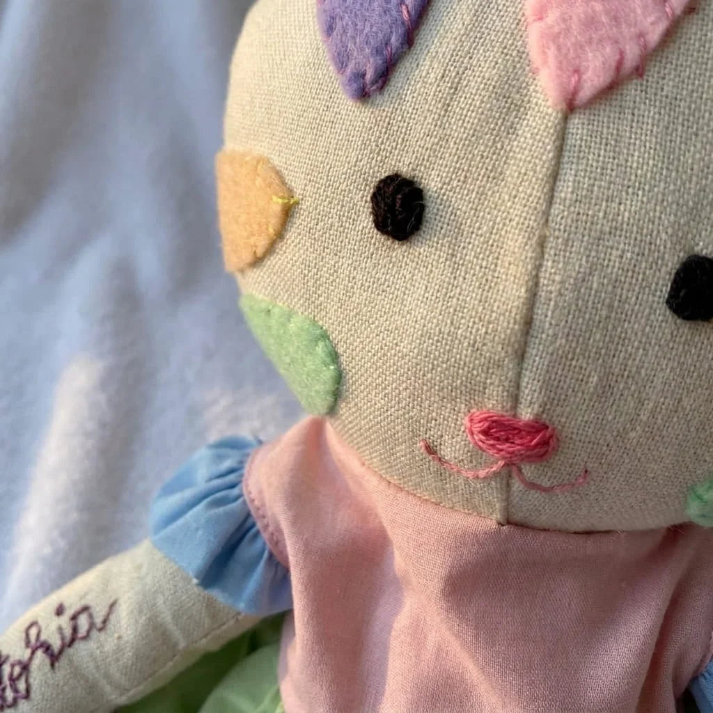 Detalle macro de la carita bordada a mano y los parches de fieltro de la gata de tela