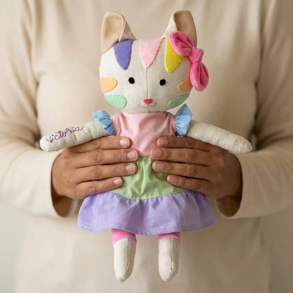 Manos sosteniendo la gata de tela personalizada con un nombre bordado para mostrar su tamaño real