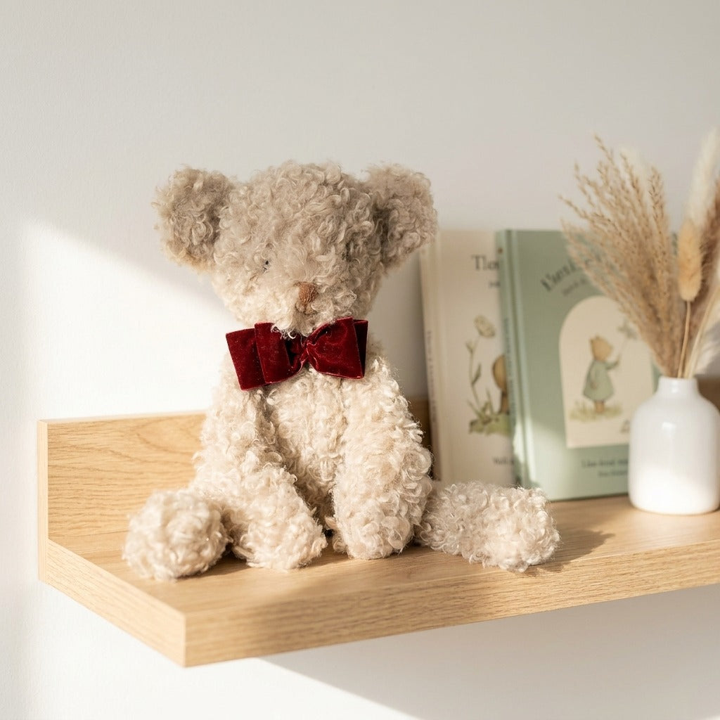 Osito rizado artesanal sentado en repisa de madera en habitación infantil estilo nórdico